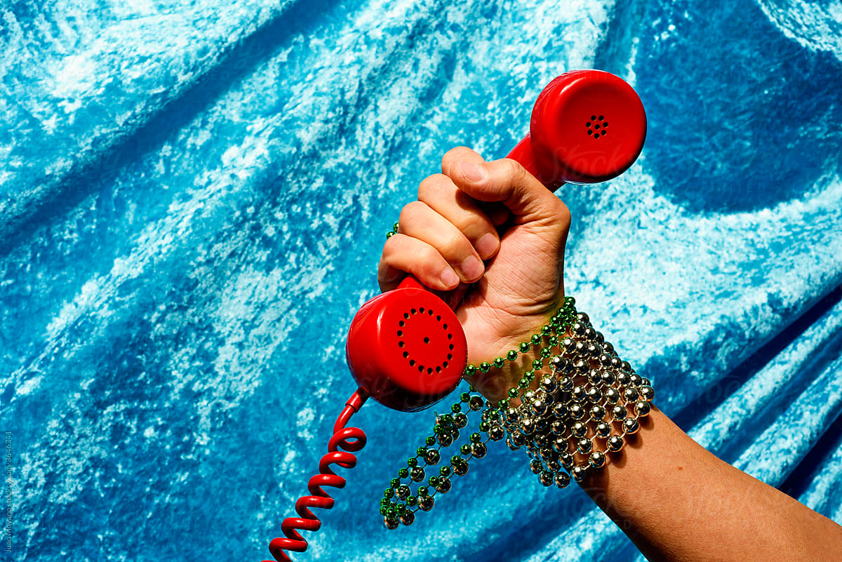 man holds the handset of a red telephone in his hand