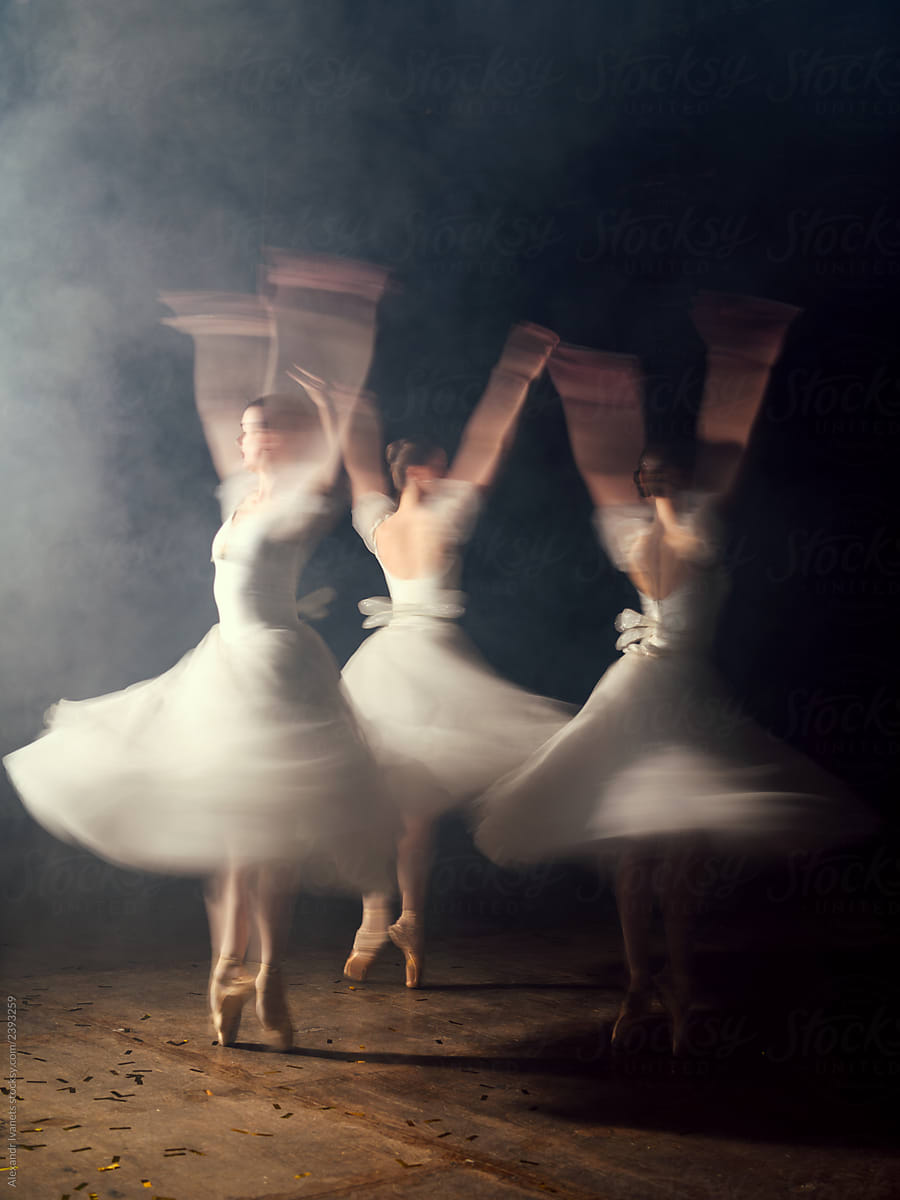 Ballerinas in dresses whirling on scene in darkness