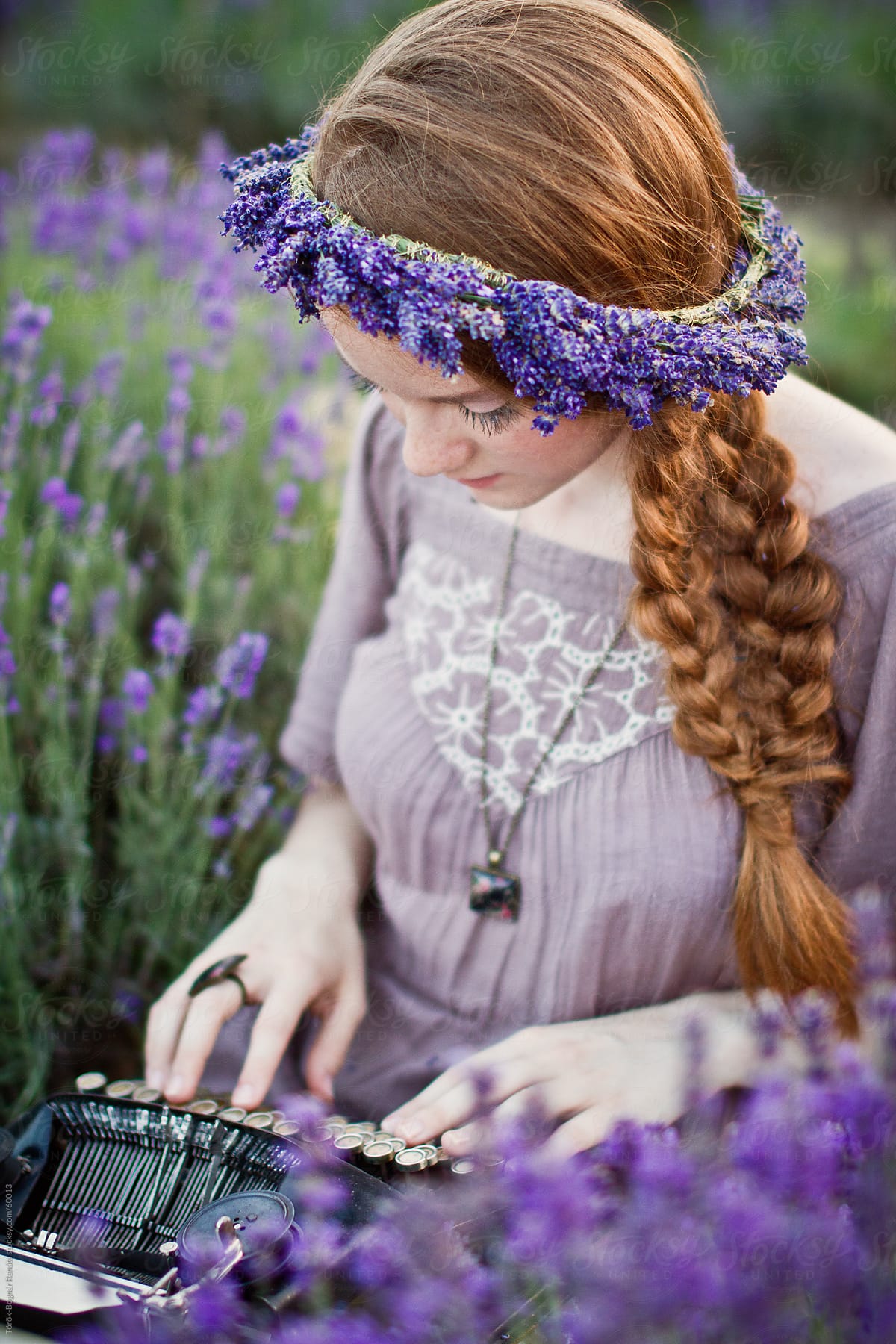 Beautiful redhaid young woman in the lavender field with a vintage typewriter