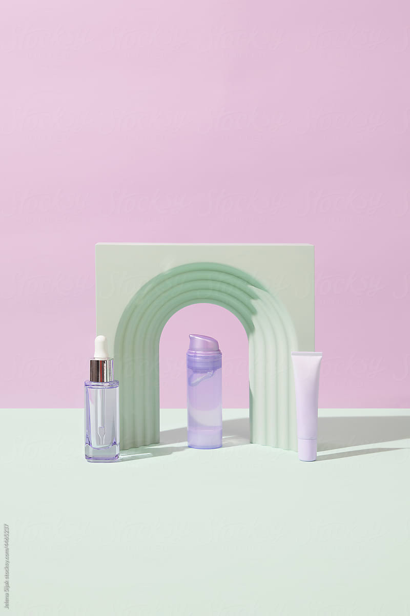 Various purple cosmetic products against a pink green background