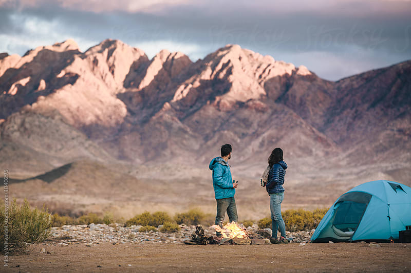 Hiking couple at their camp fire amongst rugged desert mountains