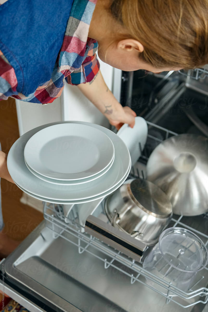 Crop female arranging plates in dishwasher
