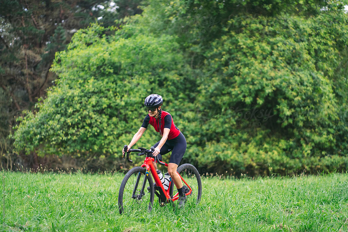 Cheerful sportswoman riding bicycle on grass