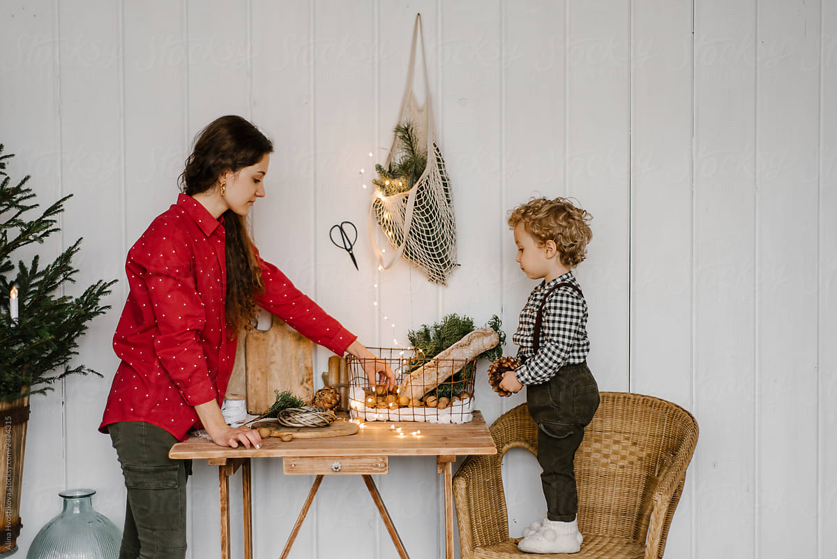 Woman and boy at table with Christmas decorations near wall