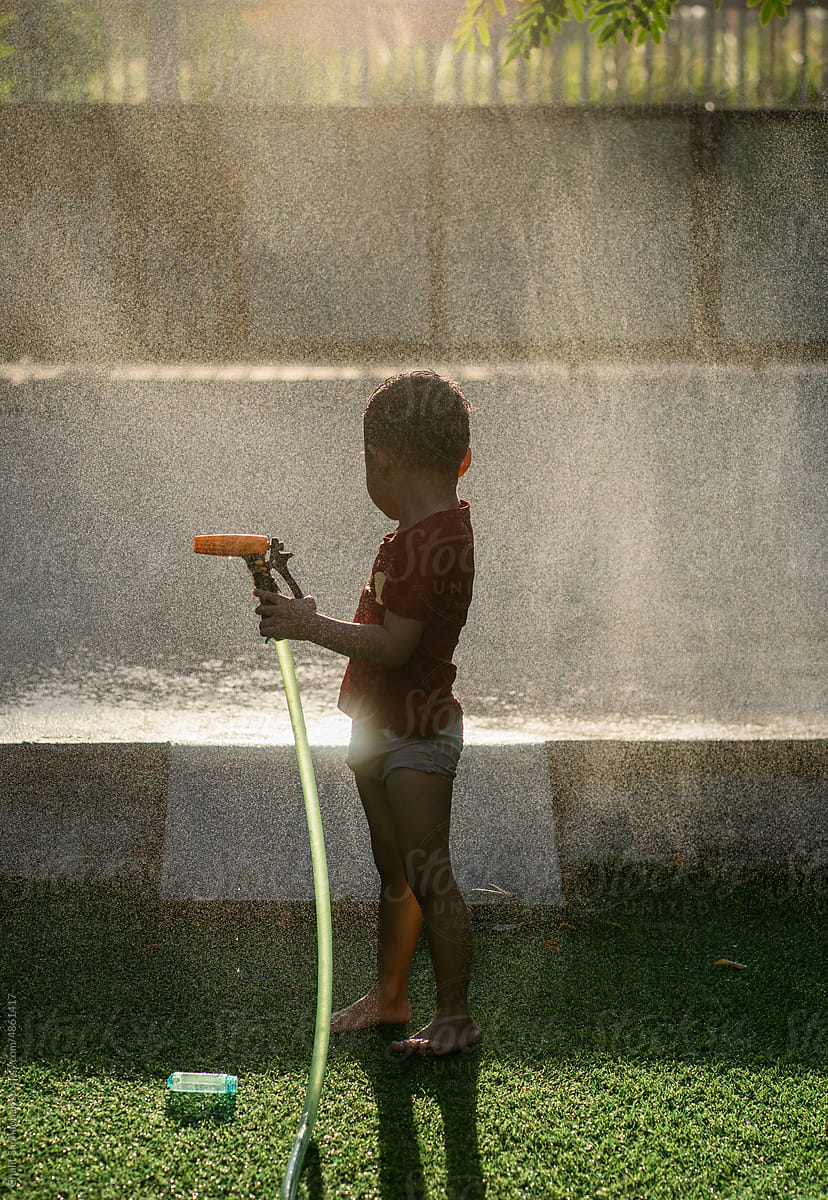Boy Spraying water in golden sunlight