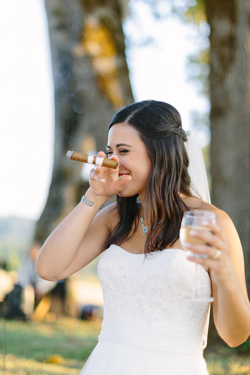 Bride Holding Glass Of White Wine And Smoking Cigar By Stocksy