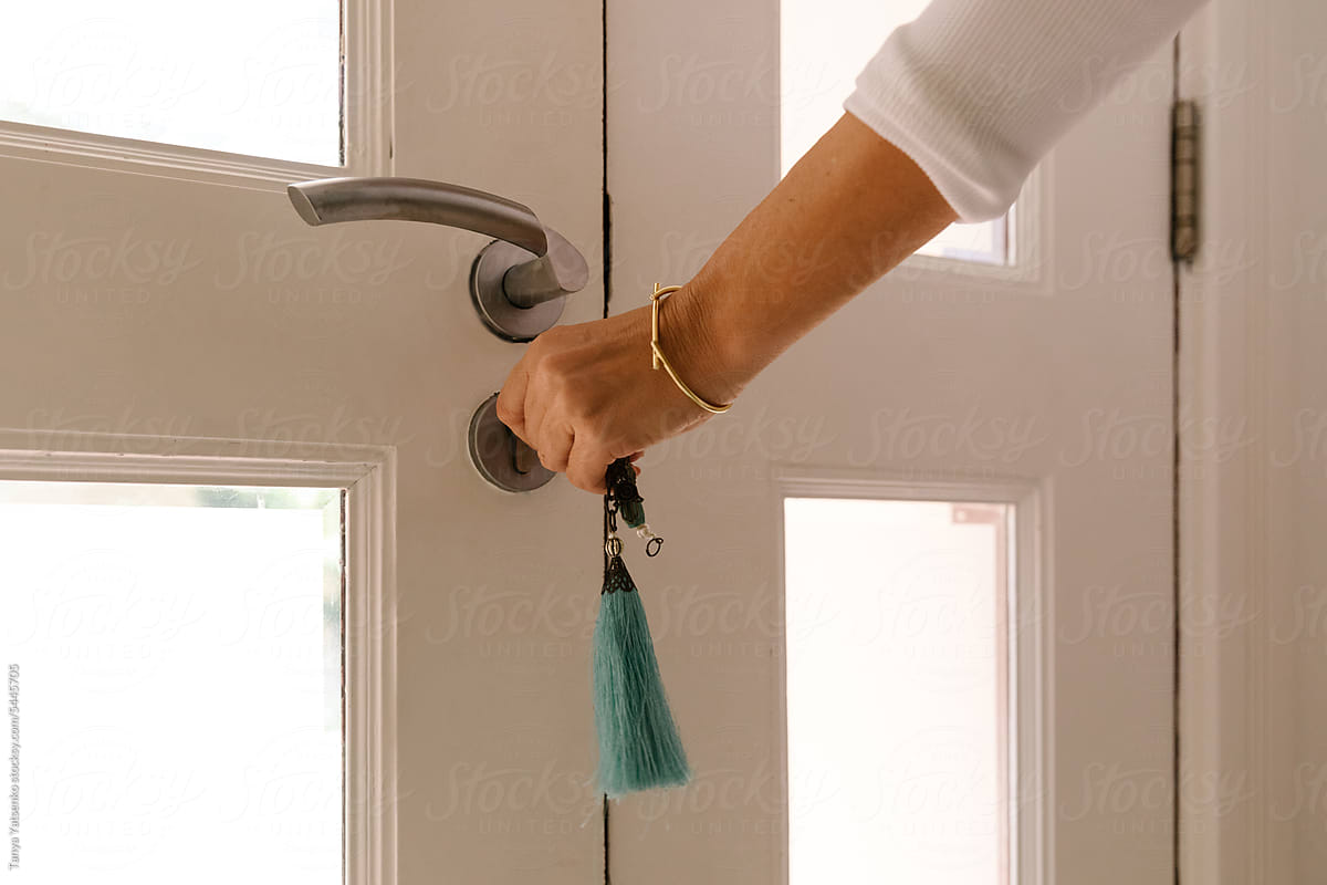 A woman closing a door with a key