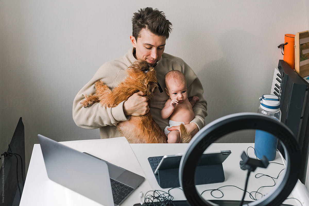 Man trying to work with a newborn and a puppy