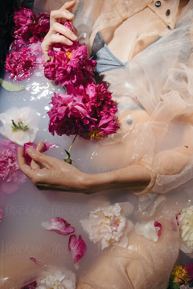 Anonymous sensual woman in milky bath with flowers