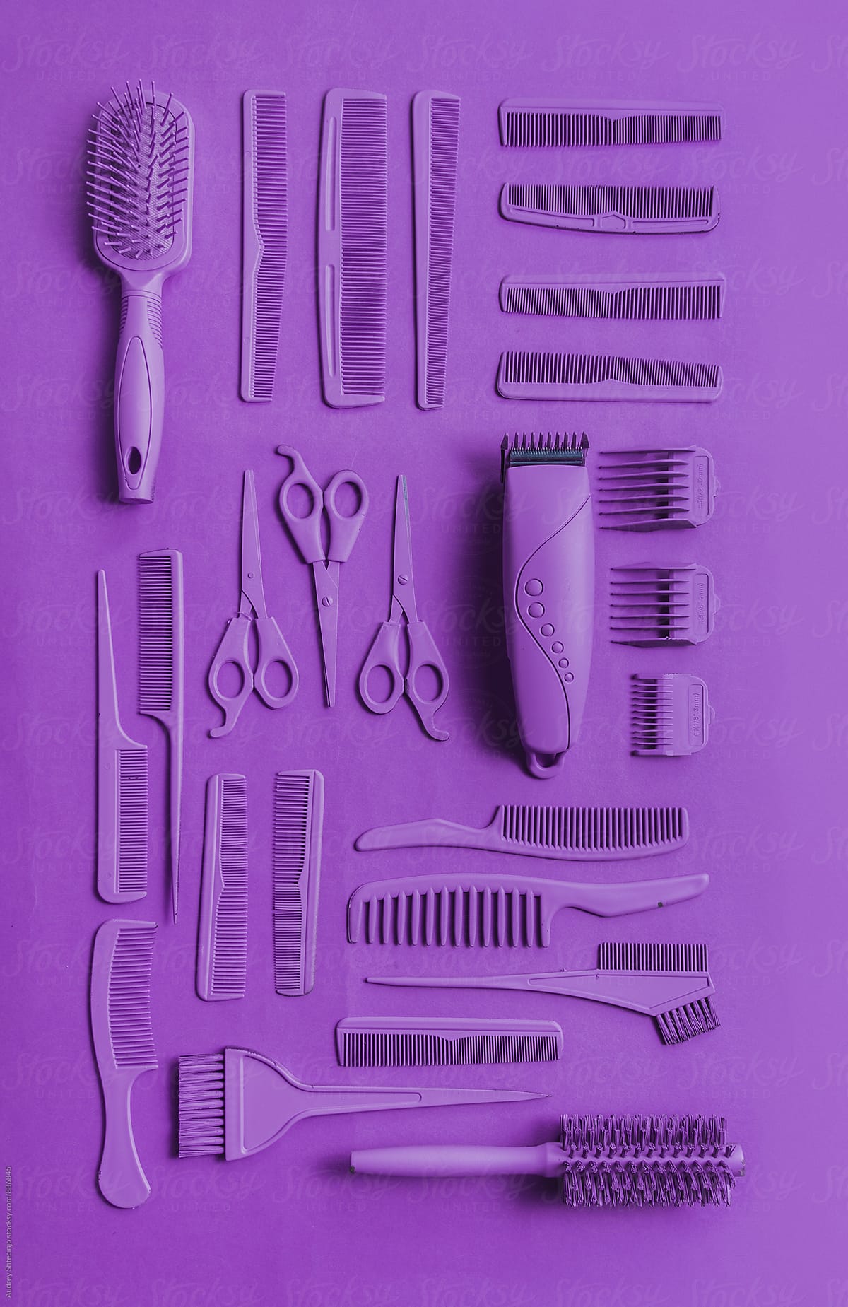 Various hairdresser tools in purple color on purple background.