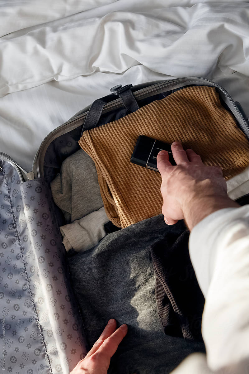 Crop unrecognizable traveler packing suitcase on bed