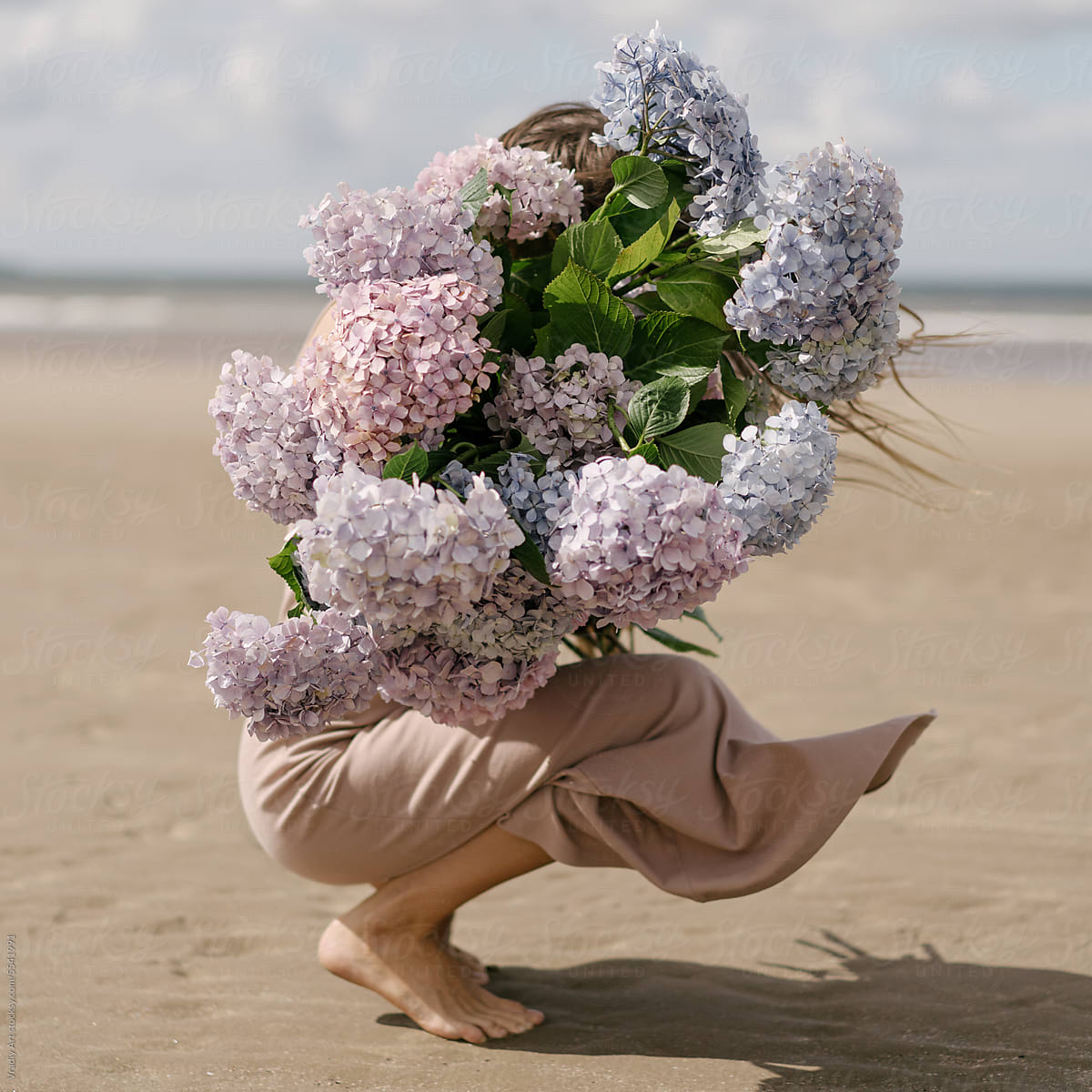 Woman with beautiful bouquet of flowers on the beach