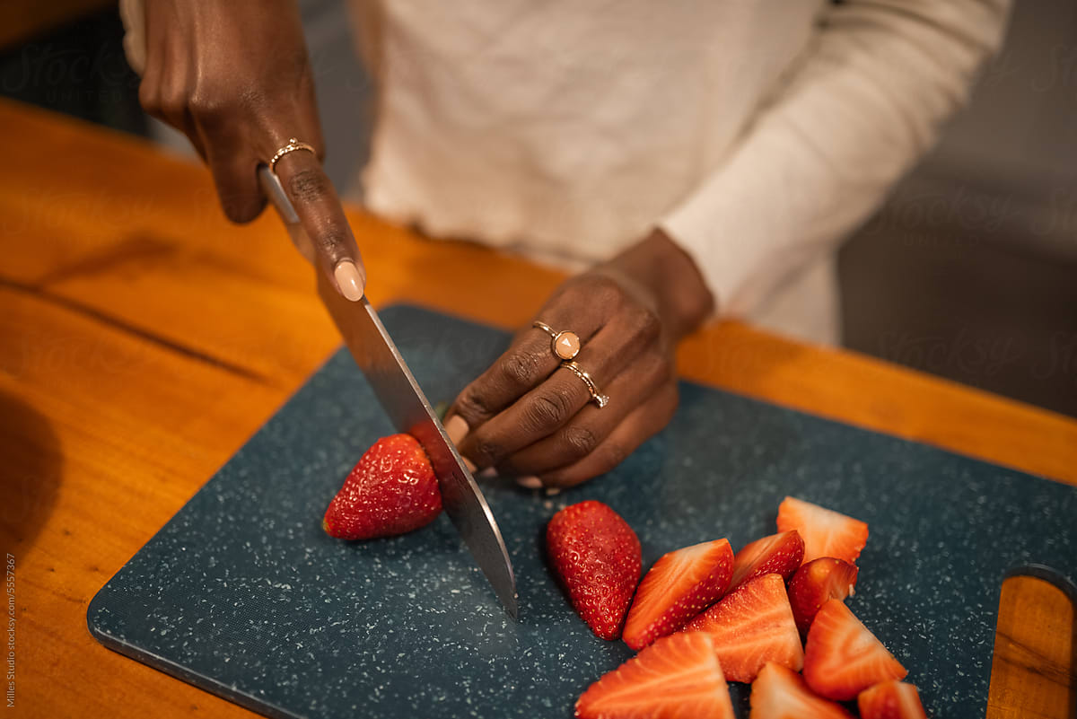 Crop black woman cutting strawberries on countertop