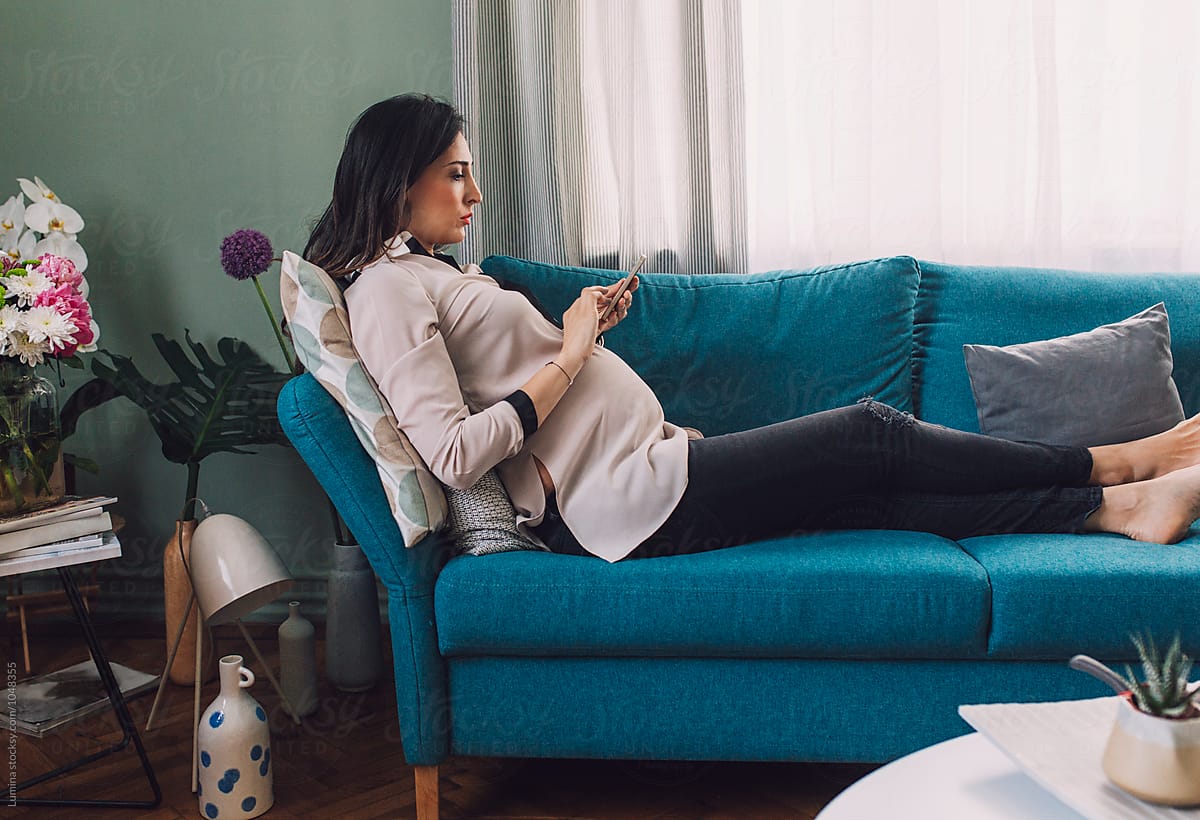 Pregnant Woman Texting On A Couch By Stocksy Contributor Lumina Stocksy