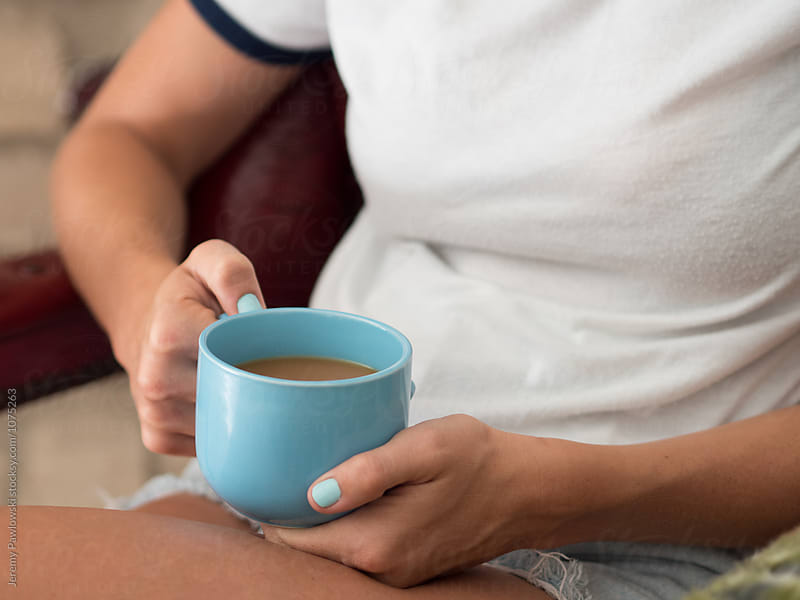 Woman with blue nail holding a blue mug full of coffee