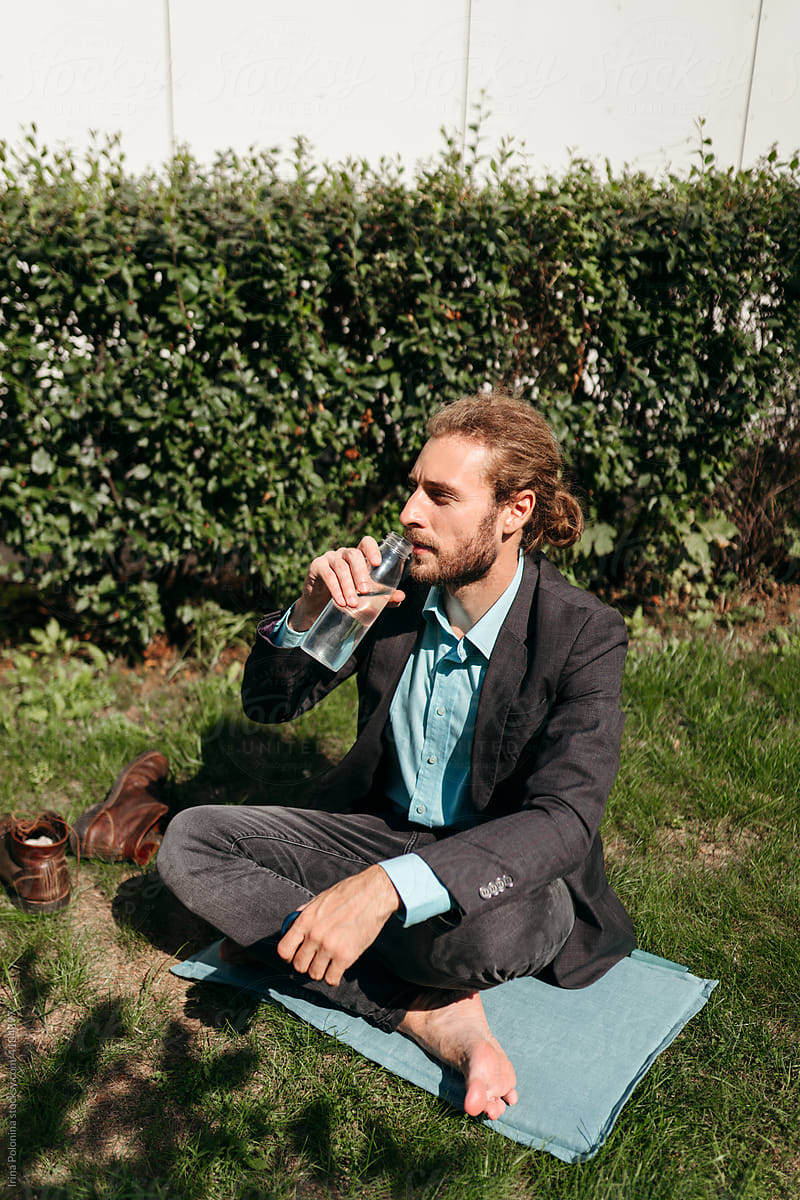 A young man drinks water bottle while resting.