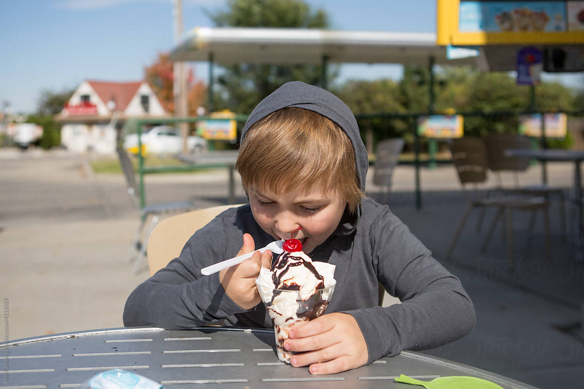 Young boy eating an ice cream sundae at a drive-in