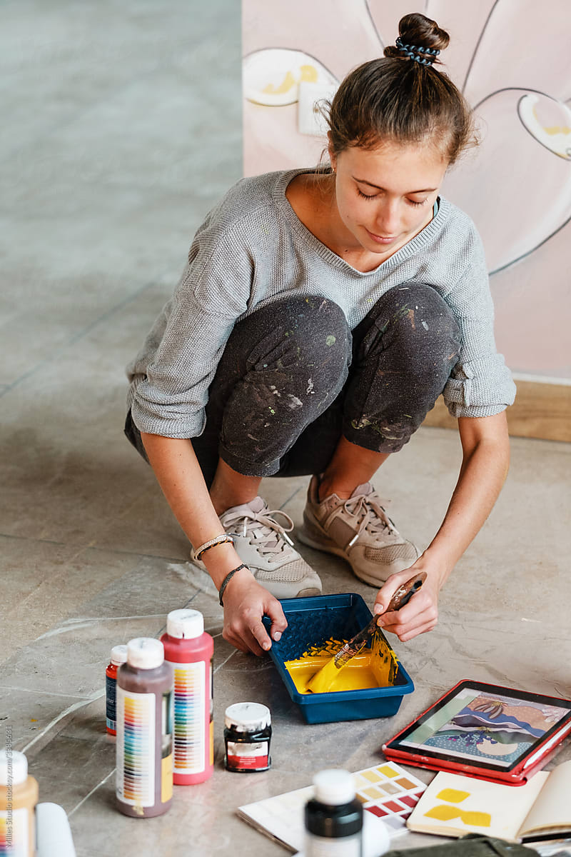 Glad female designer preparing paint for renovation works