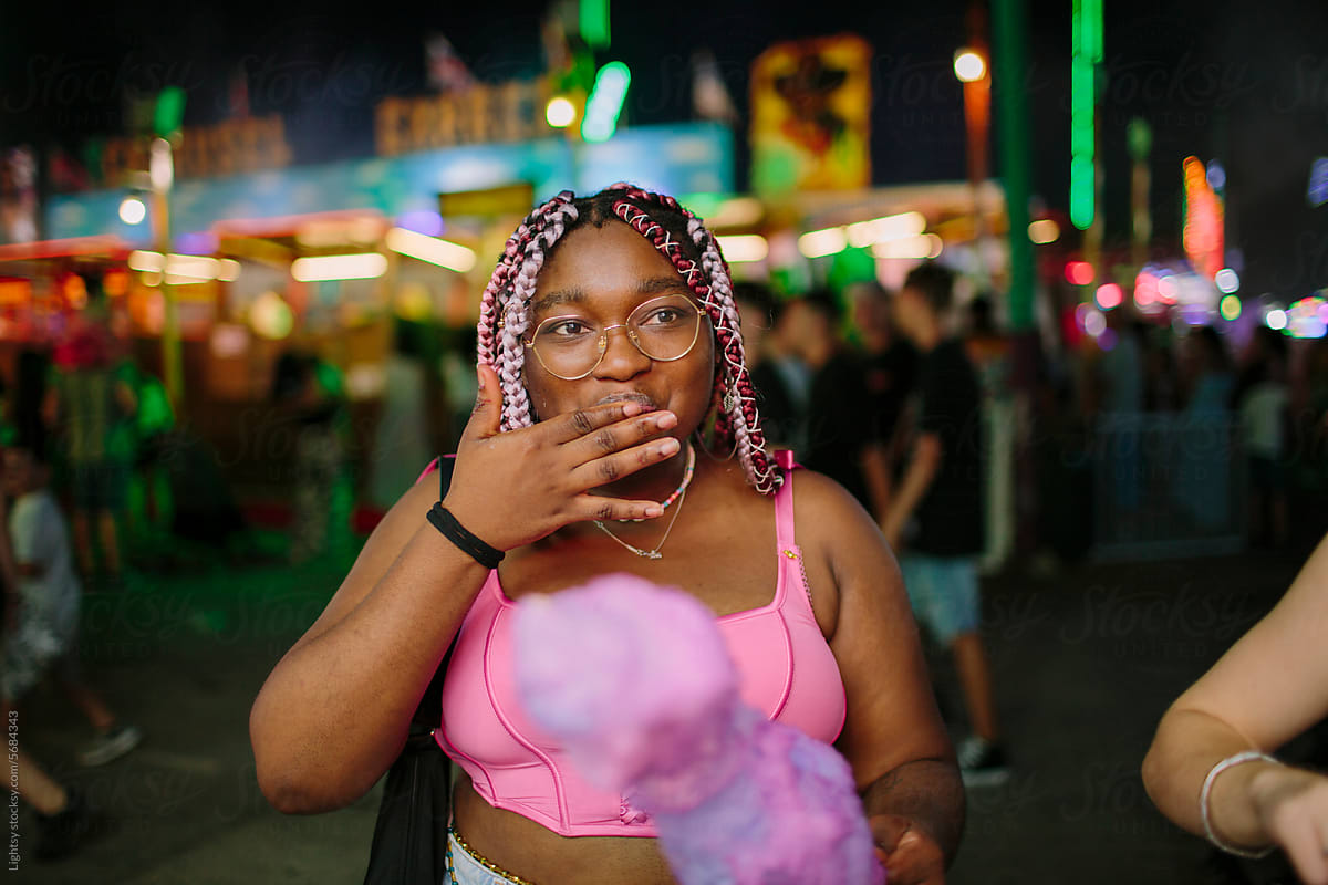 African American woman having cotton candy at a fair at night