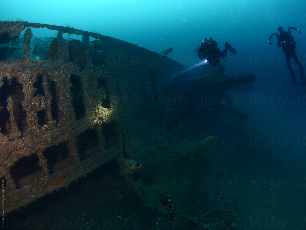 wreck underwater in blue water scuba divers to explore metal on ocean
