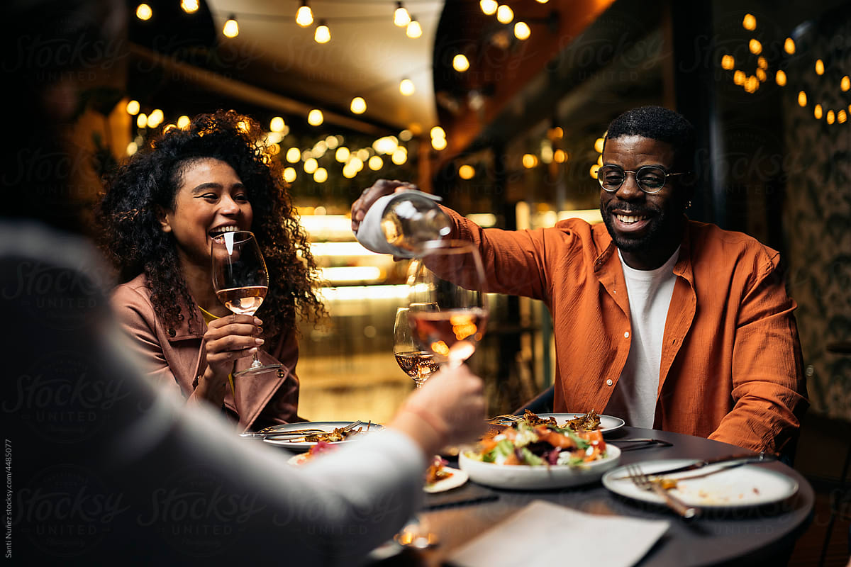 Cheerful diverse friends drinking wine in restaurant