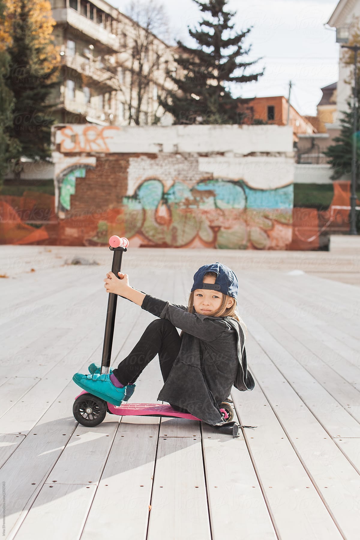 Blond little girl with a pink push scooter