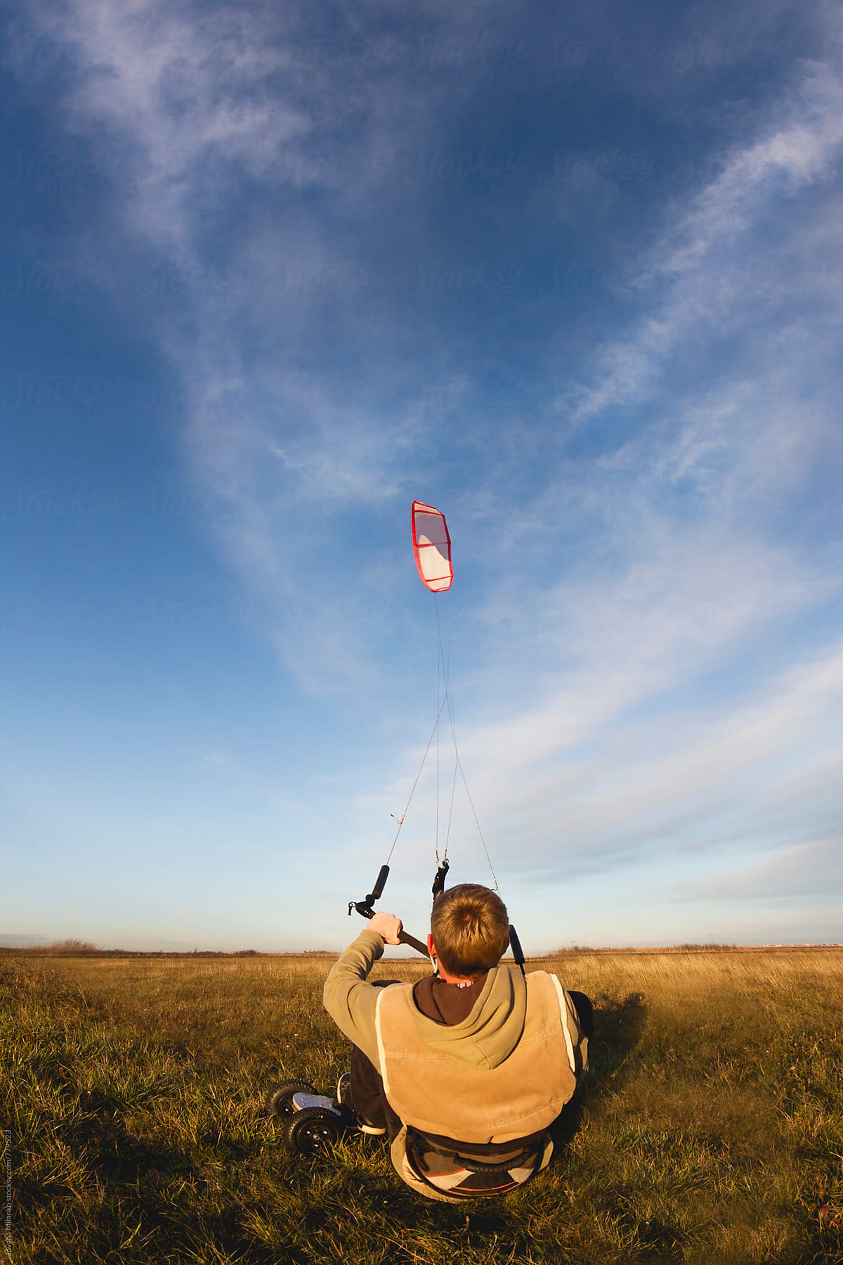 Young man kiteboarding in the field at sunset