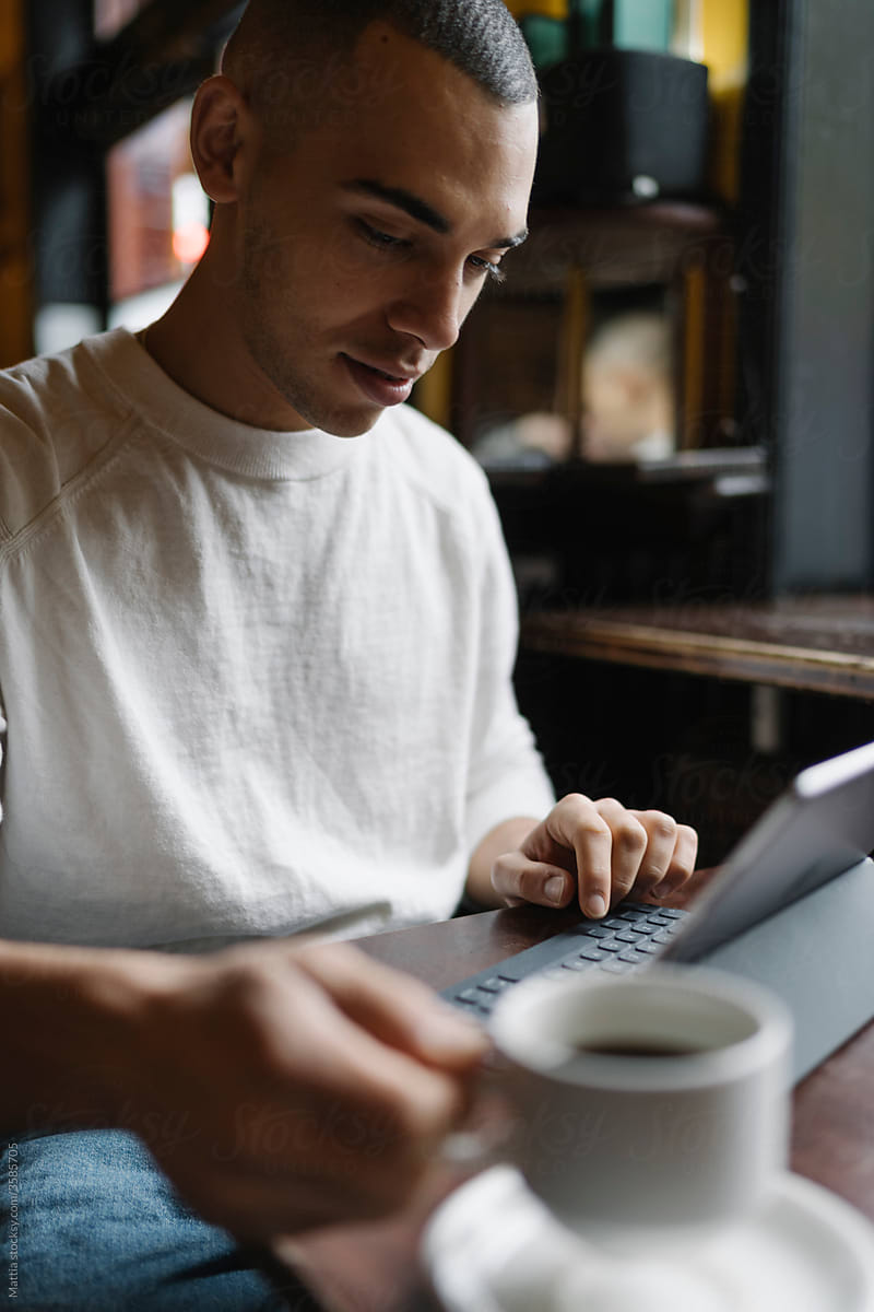 Man Drinking a Coffee and Working from a Coffee Shop