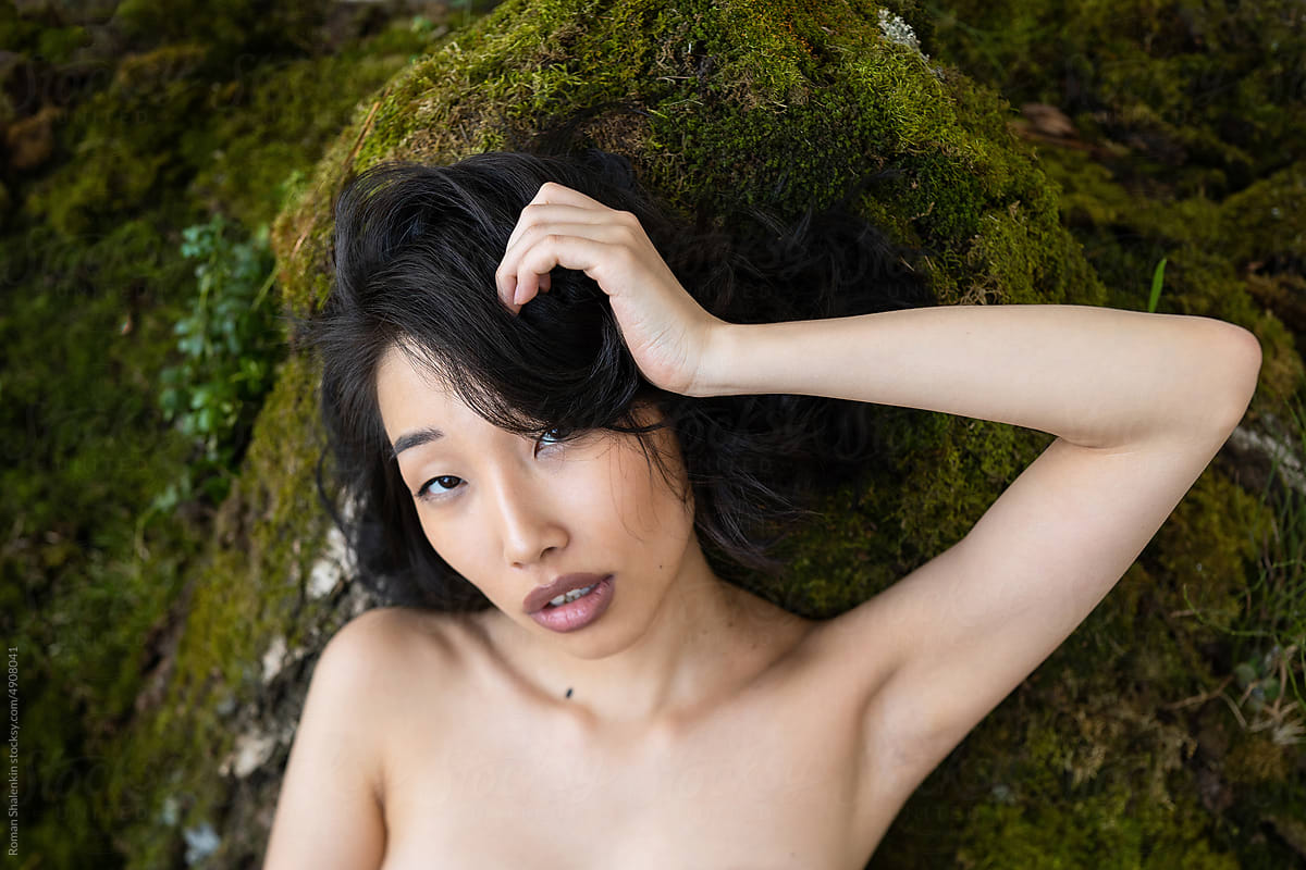 Attractive Asian woman lying on rocky surface