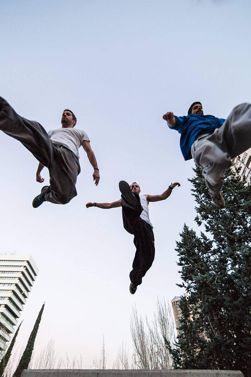 Three men jumping during a parkour training at sunset