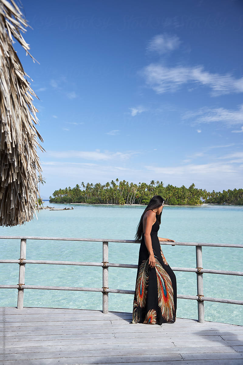 Woman looking at view on deck of overwater bungalow