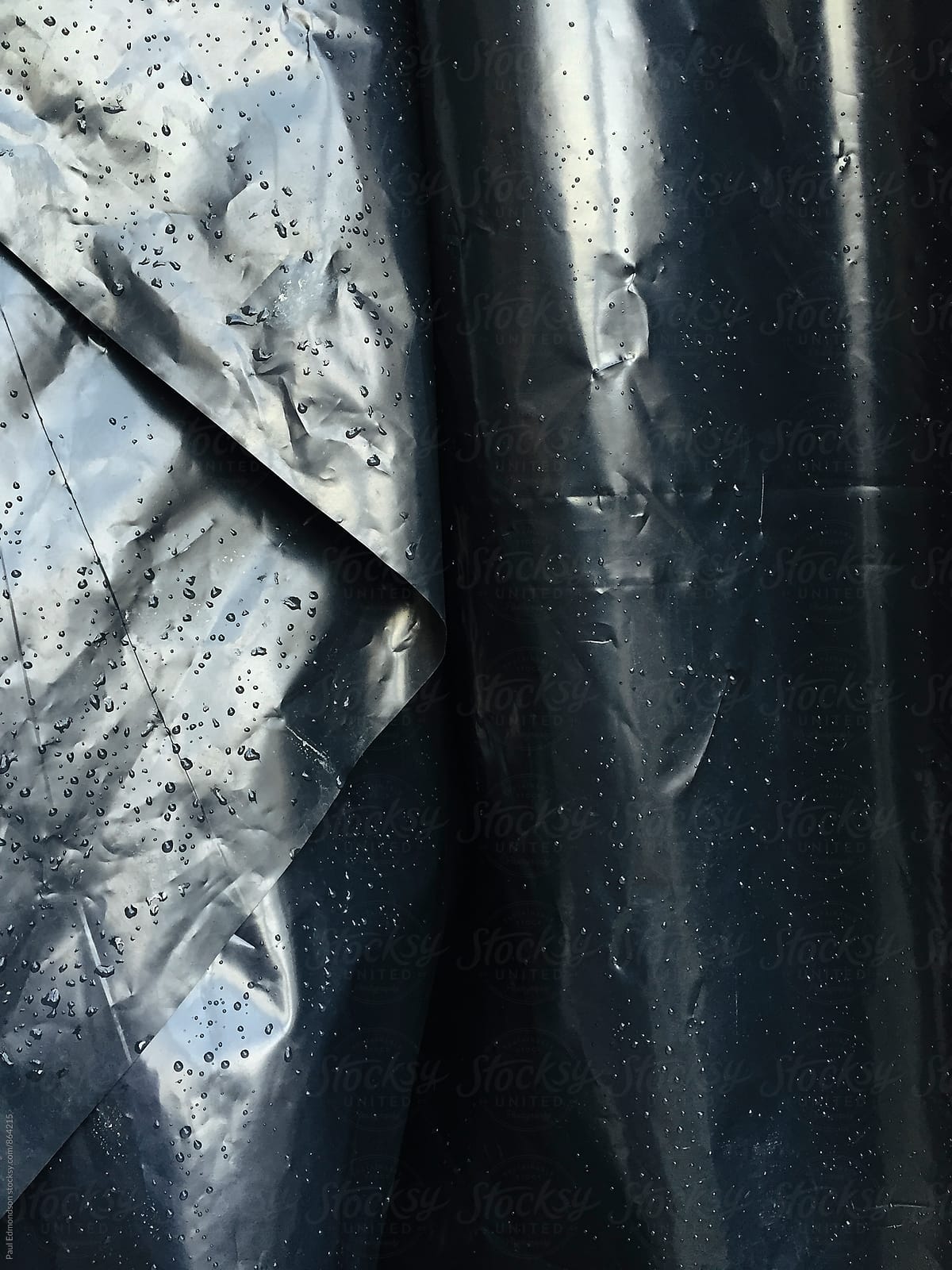 Close up of wet, black plastic sheeting covering construction site