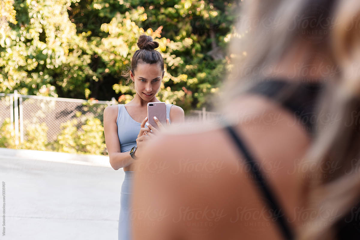 Young female athlete taking photo of friend in yard