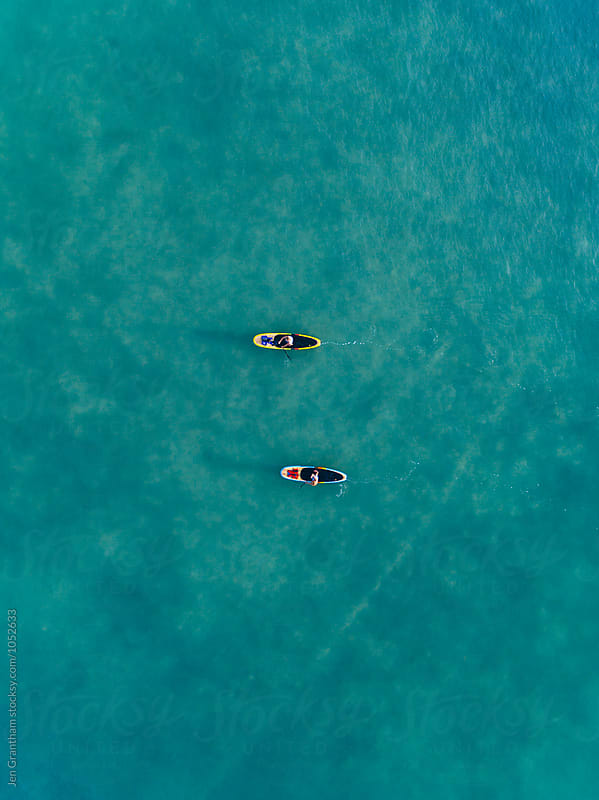 Aerial drone image of two women stand up paddleboarding in the o