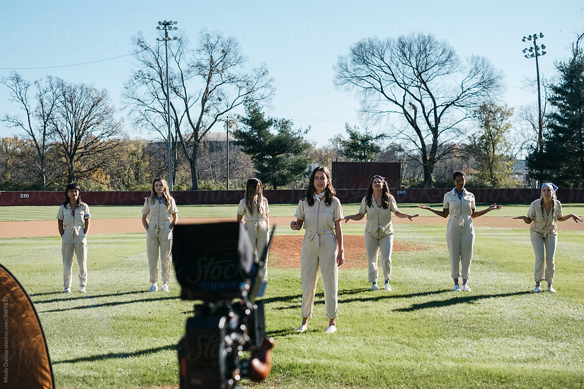 Young women prepare choreographed movements on a baseball field