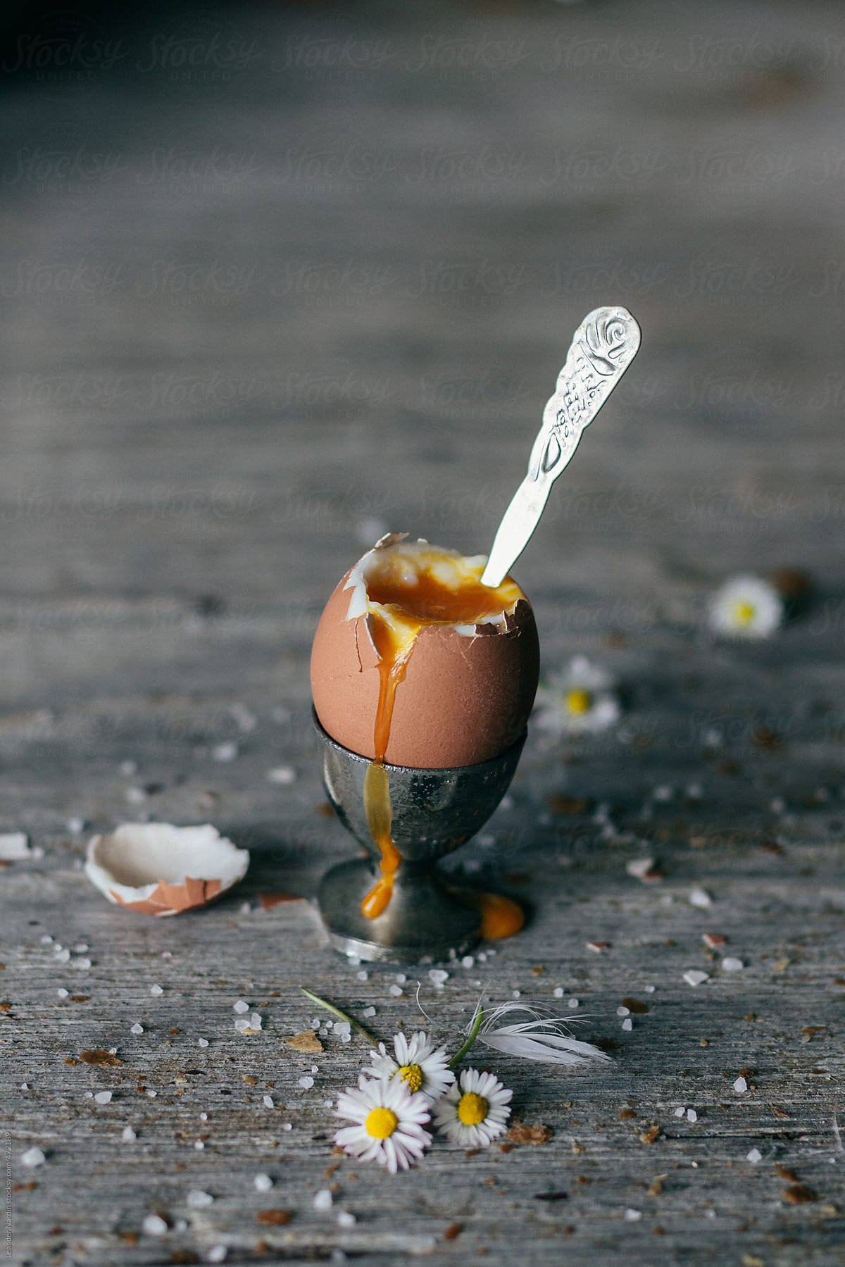 broken boiled egg in silver eggcup on wooden board