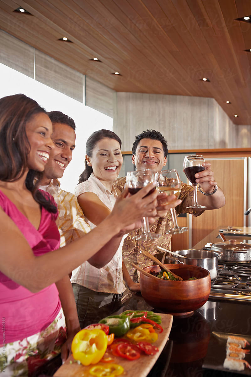 Group of multi-ethnic friends doing a toast with wine in the kitchen