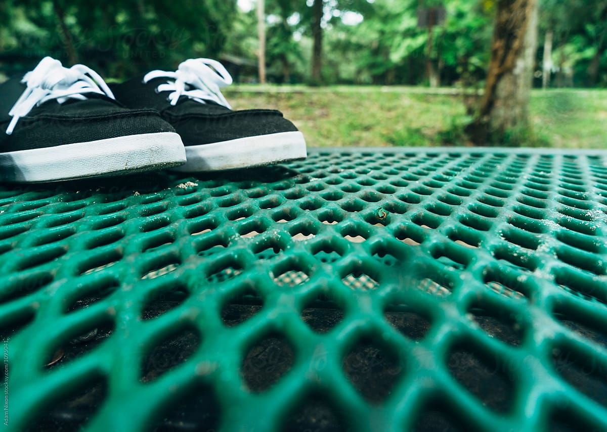 Black sneakers on a green picnic table