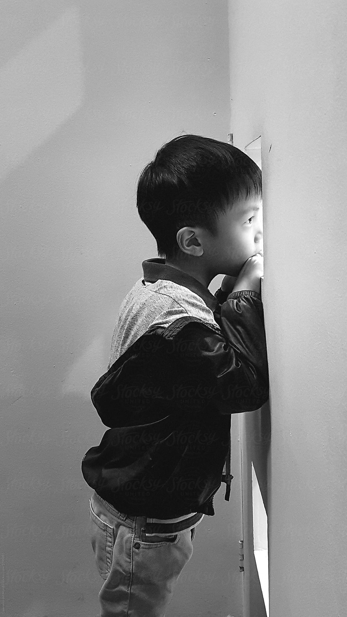 Young child peeking through a hole on the wall.