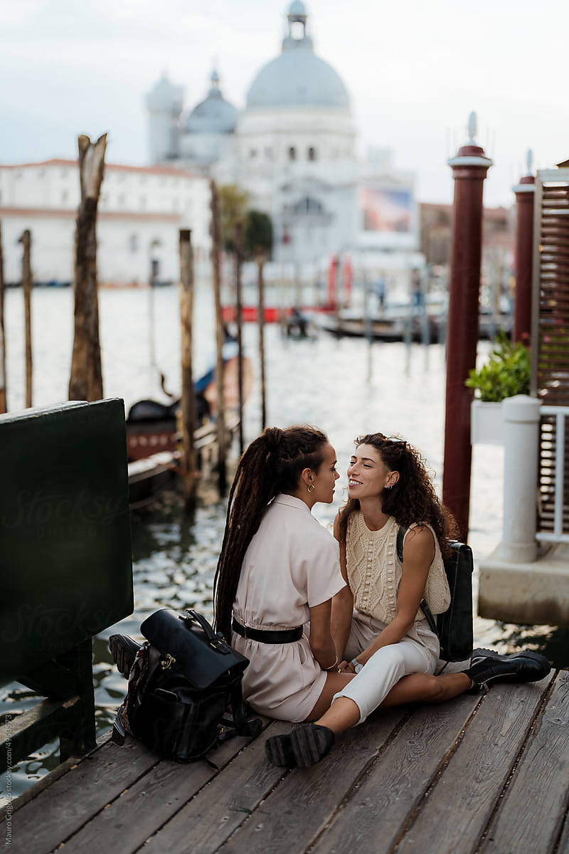 Happy women sitting together on a pier in Venice