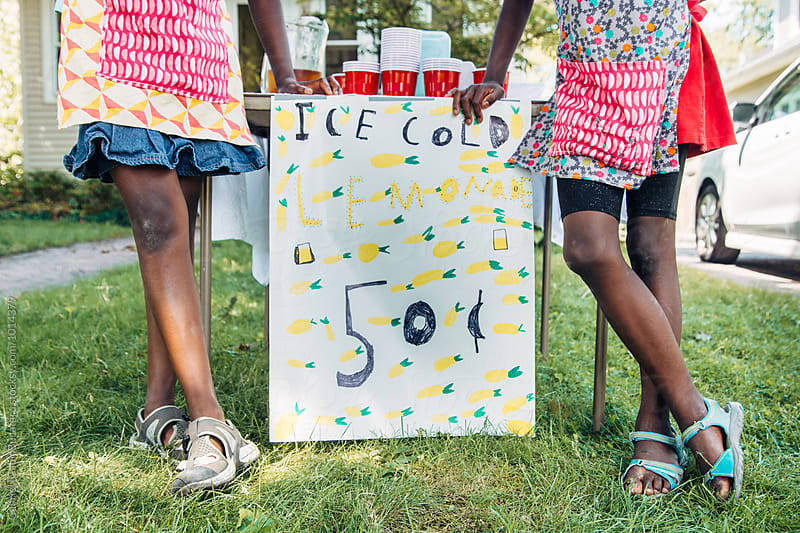 Two African American girl\'s legs by their lemonade stand