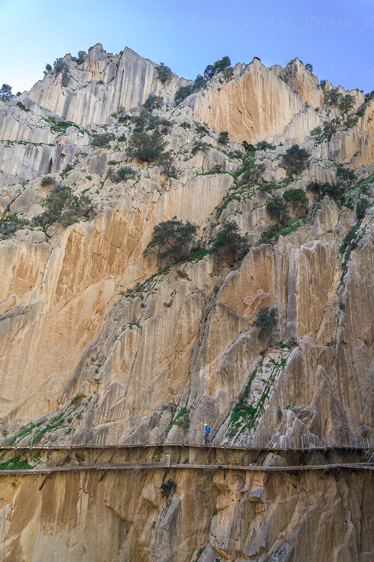 Climber walking on wooden walkway at the edge of a cliff in Caminito del Rey
