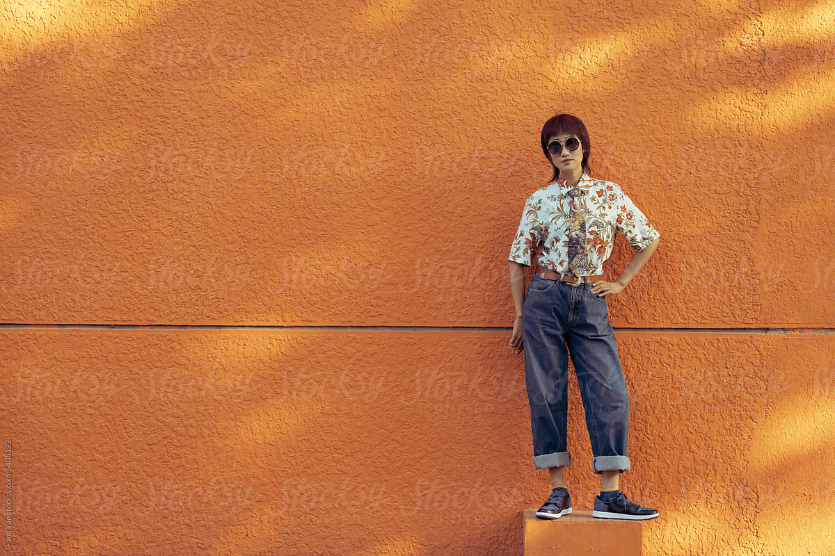 Fashionable confident Woman Poses Against Orange Wall