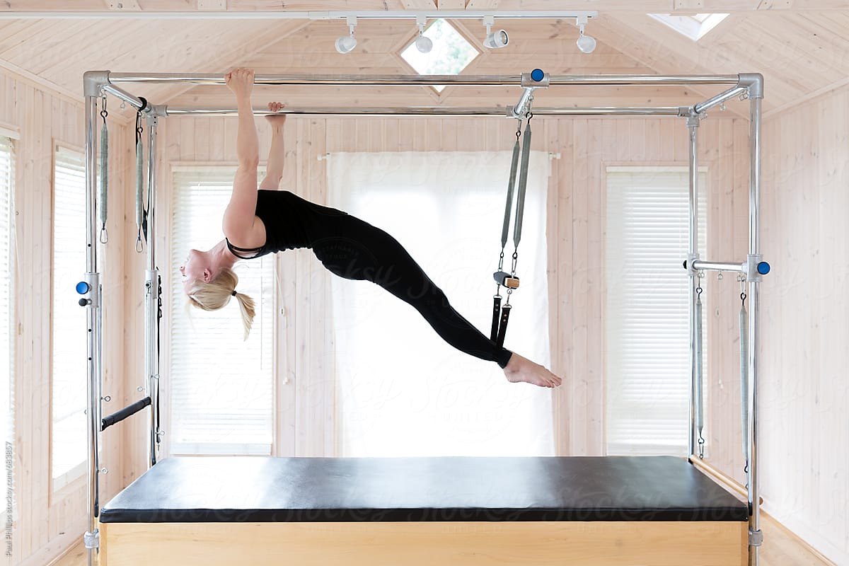 Woman Undertaking Pilates Stretching Exercise On The Trapeze Table