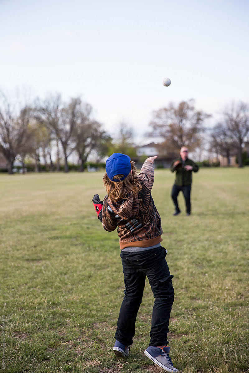 Father and son playing catch in a field in a neighborhood