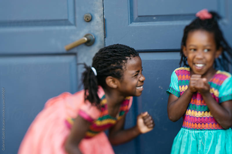 Two Black Girls Laughing In Front Of A Blue Door By Gabriel Gabi