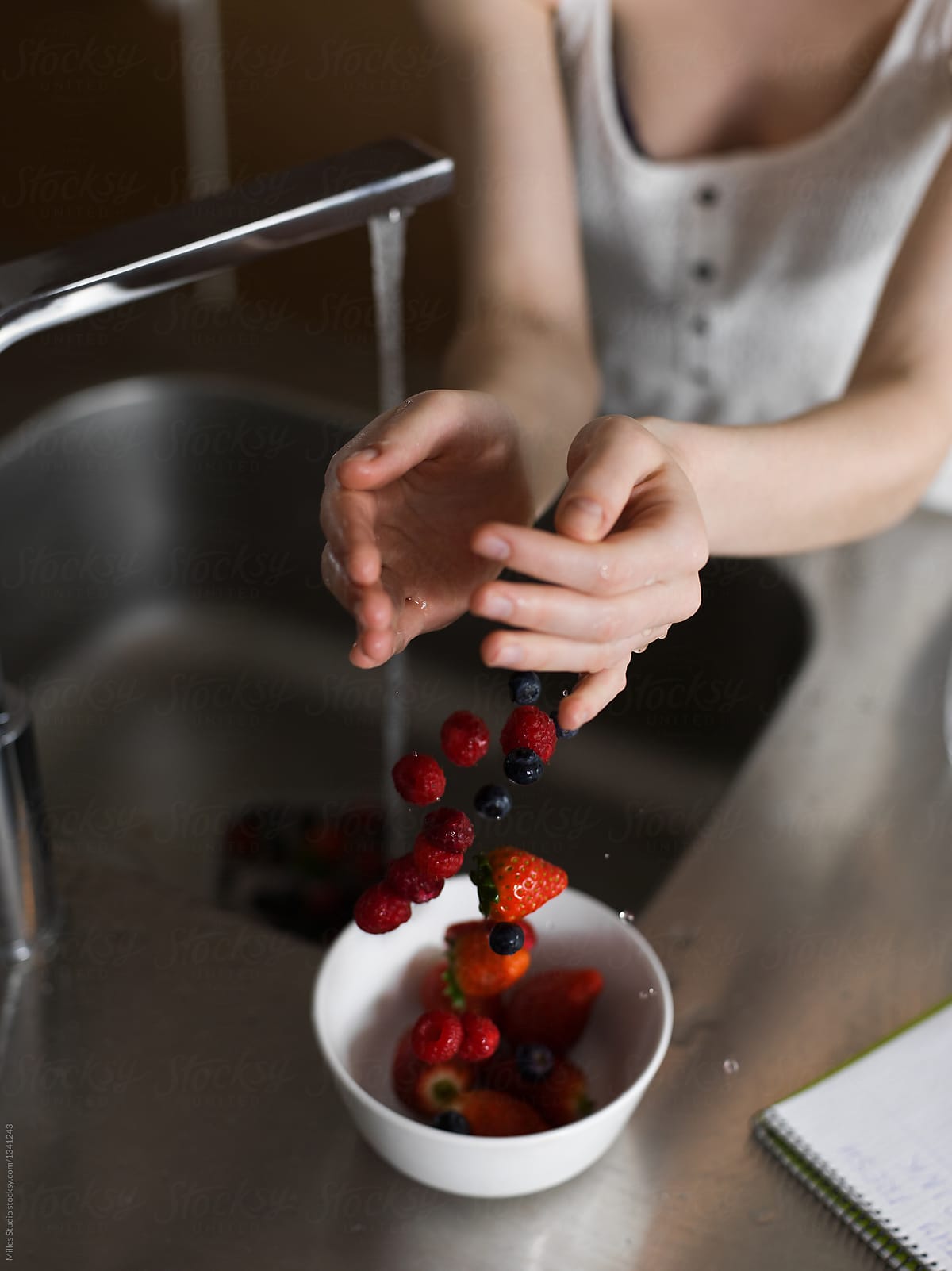 Woman putting berry to bowl