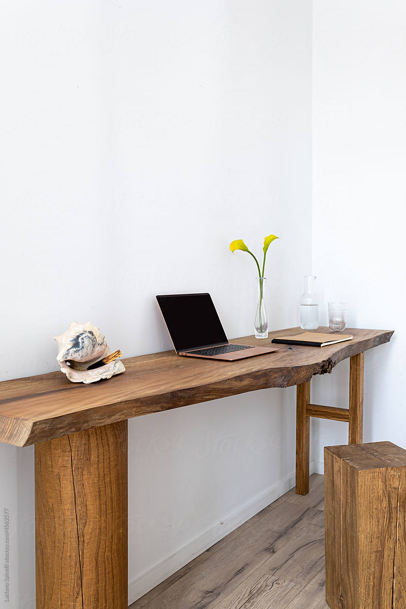 Cosy workspace with wooden desk, laptop, notebook and flowers