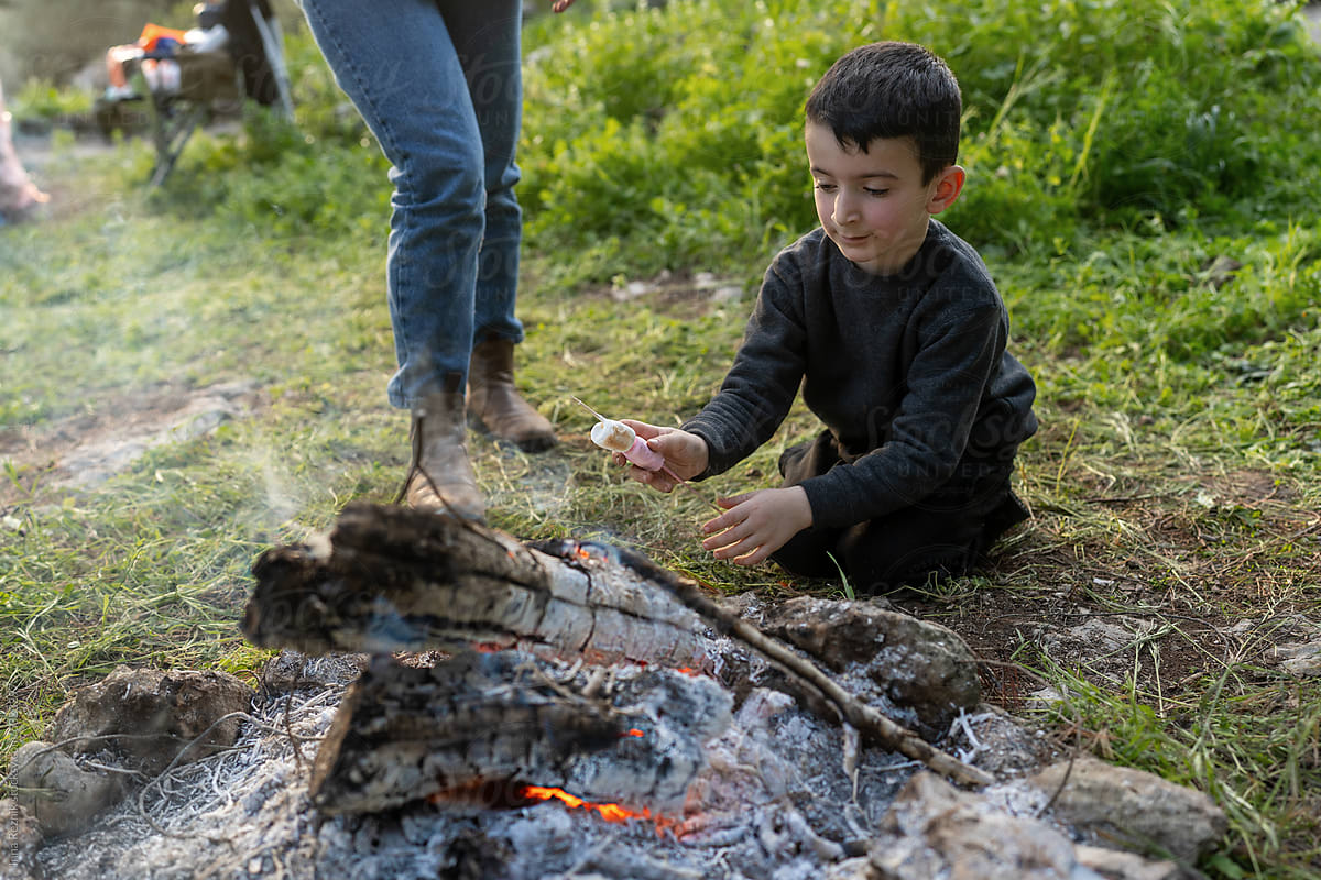Boy Roasting Marshmallow With Family Over Fire.