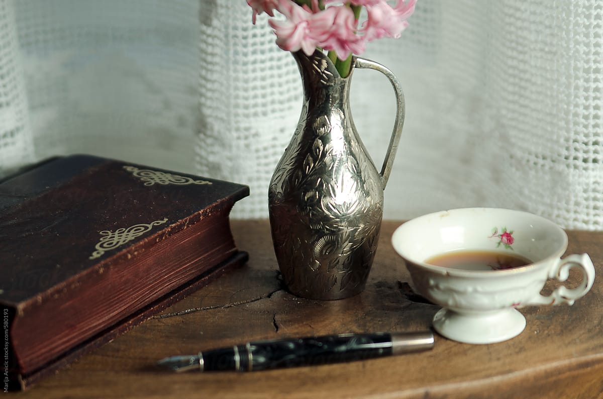 Silver vase with pink flowers,cup of coffee,notebook and pen